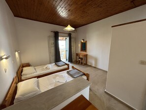 Um quarto pequeno e acolhedor com duas camas de madeira, uma escrivaninha e um espelho.