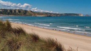 A beach with a clear view of the ocean and distant cliffs. - Don Pedro (Aviles)