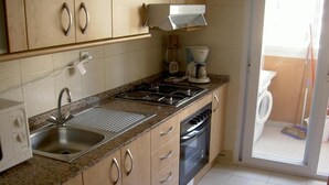 Une cuisine équipée d’un évier, d’une cuisinière, d’un four et d’une machine à café.