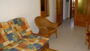 Un salon avec un canapé et un fauteuil en osier.