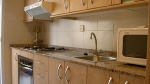 Une cuisine dotée de meubles en bois, d’un évier en acier inoxydable, d’un four à micro-ondes et d’un four encastré.