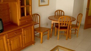 Un coin repas avec une table et des chaises en bois, un meuble avec des tiroirs et un tableau encadré au mur.