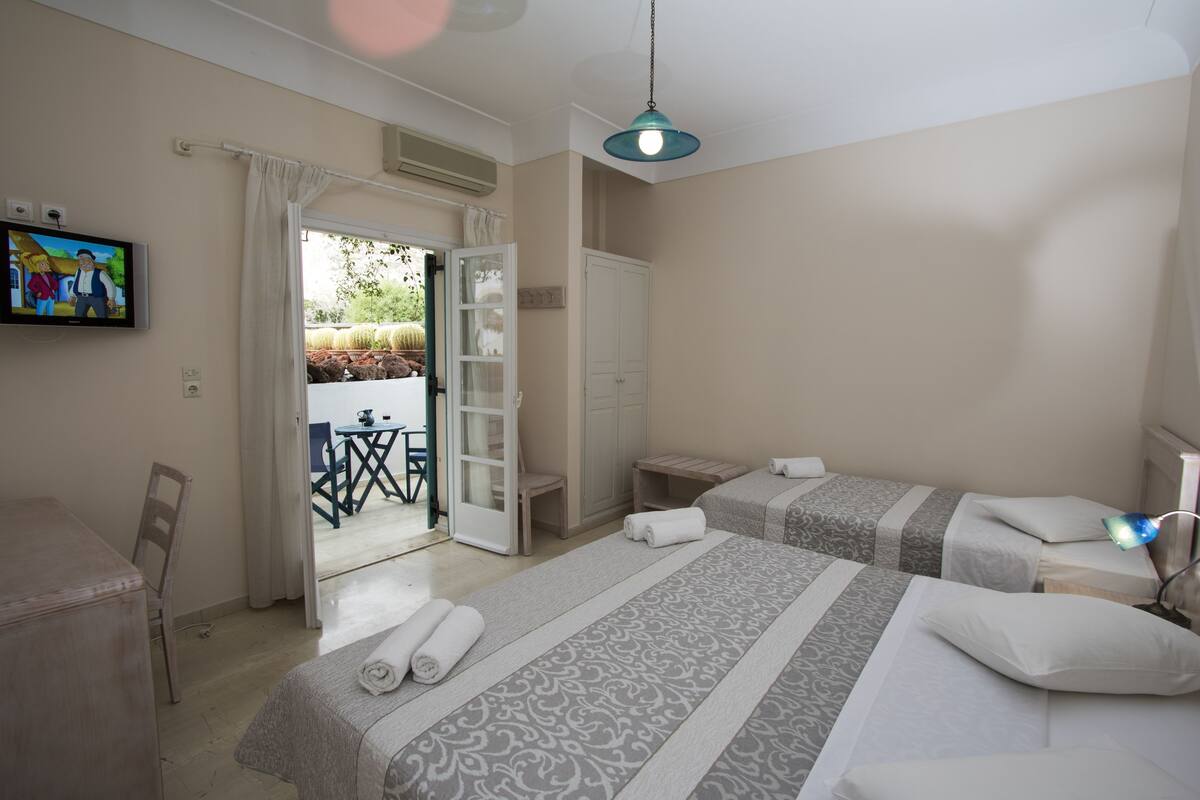 Une chambre d’hôtel avec deux lits, une télévision, un bureau et une chaise.