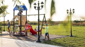 A playground with a swing set, a slide, and a covered play area.