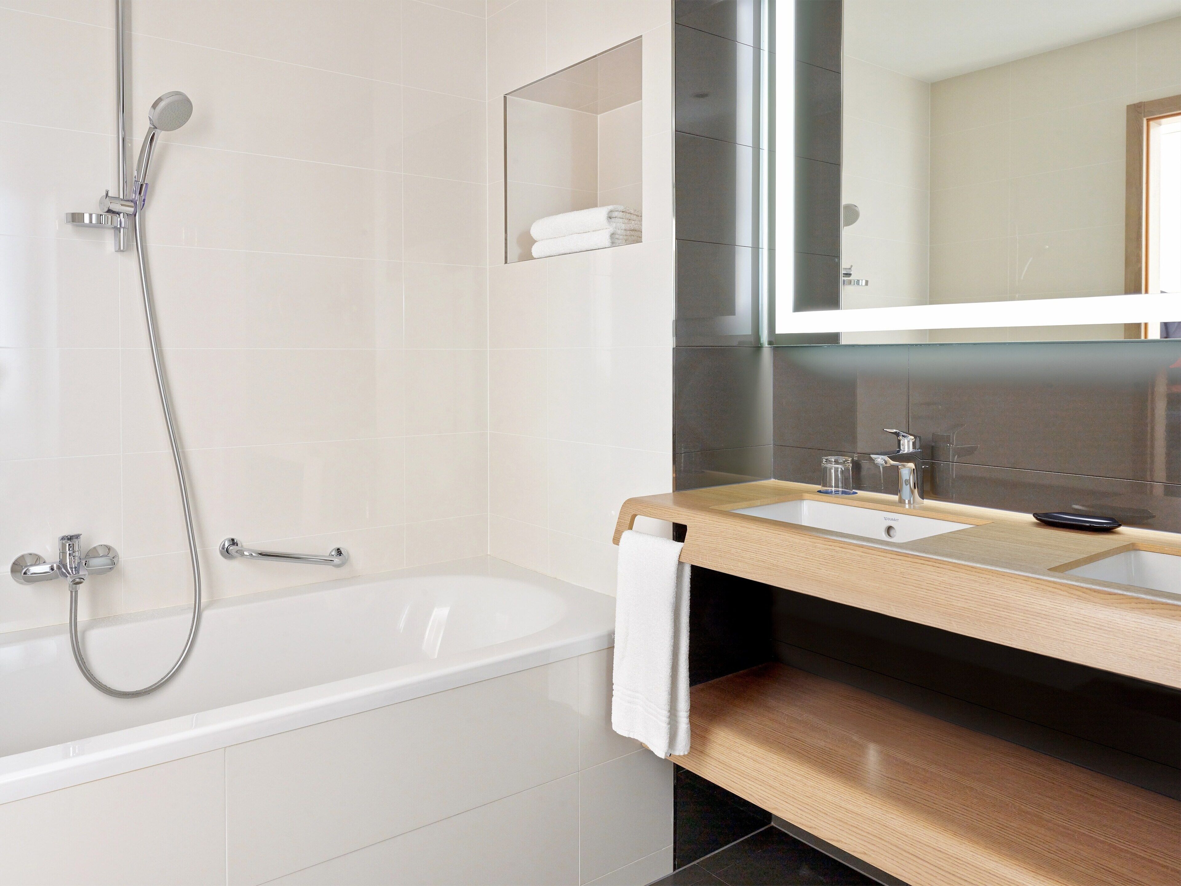 A modern bathroom with a bathtub, a shower, a sink, and a mirror.