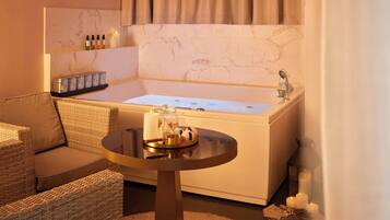 A bathroom with a bathtub, a small round table with toiletries, and a wicker chair.