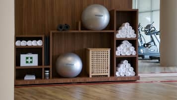 Un gimnasio con equipo de ejercicios, una pared de madera y una cinta de correr al fondo.