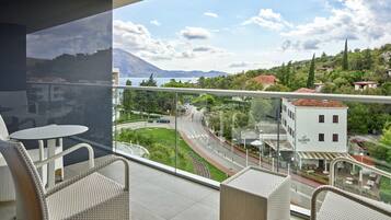 A balcony with wicker furniture and a view of a road, buildings, and mountains.