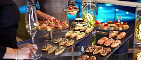 A buffet table with various appetizers and a person serving food.