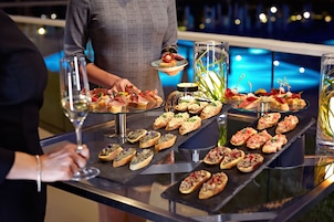 A buffet table with various appetizers and a person serving food.