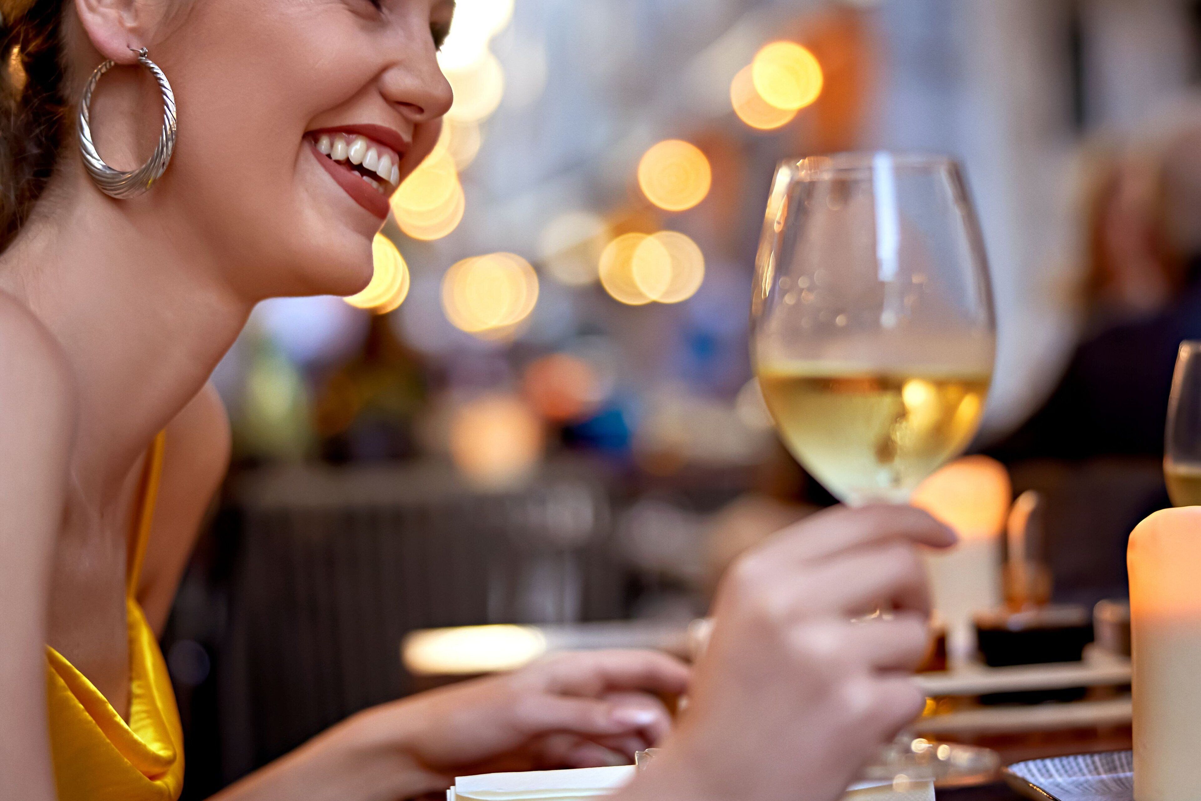 A person holding a wine glass at a table with a candle, suggesting a dining setting.