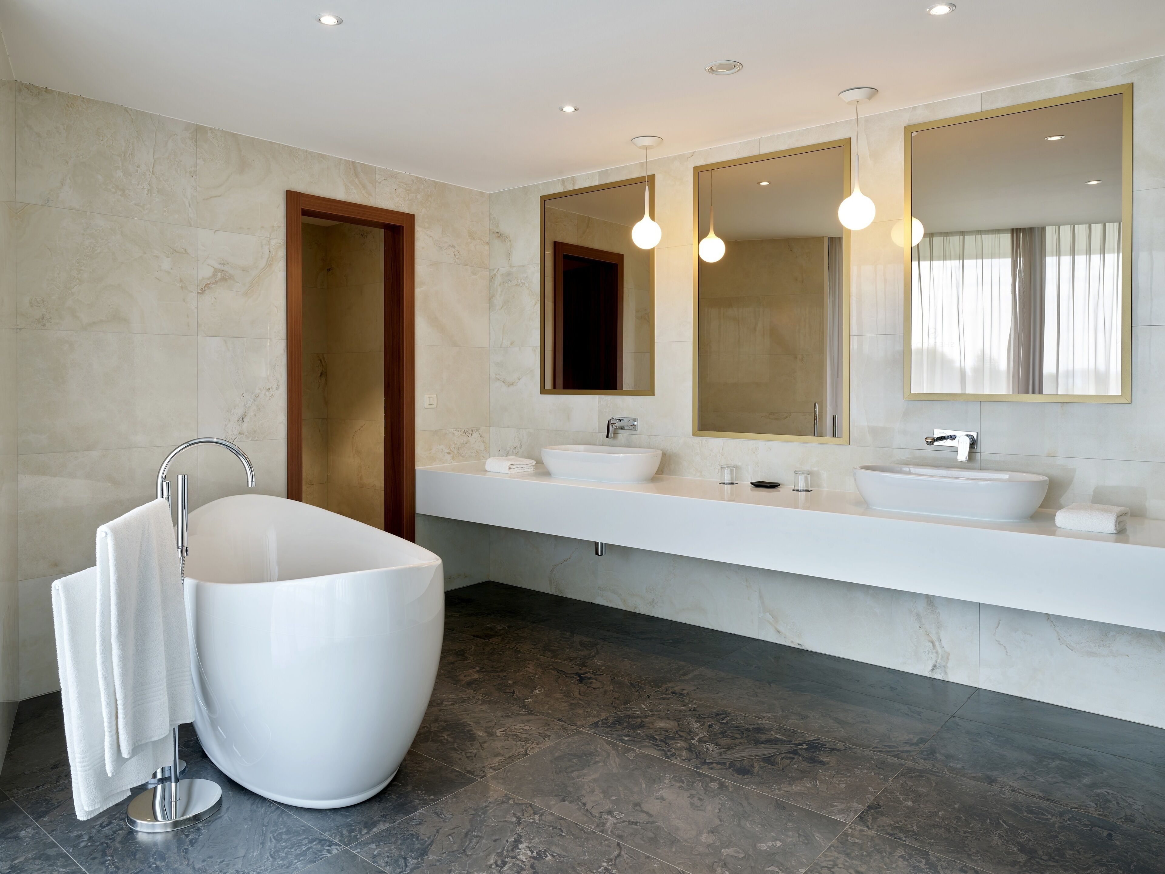Ein modernes Badezimmer mit einer freistehenden Badewanne, einem Waschtisch mit zwei Becken und einem großen Spiegel.