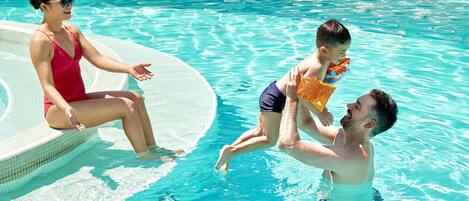 Ein Schwimmbecken mit klarem, blauem Wasser, einer gefliesten Kante und einer Person, die am Rand sitzt.