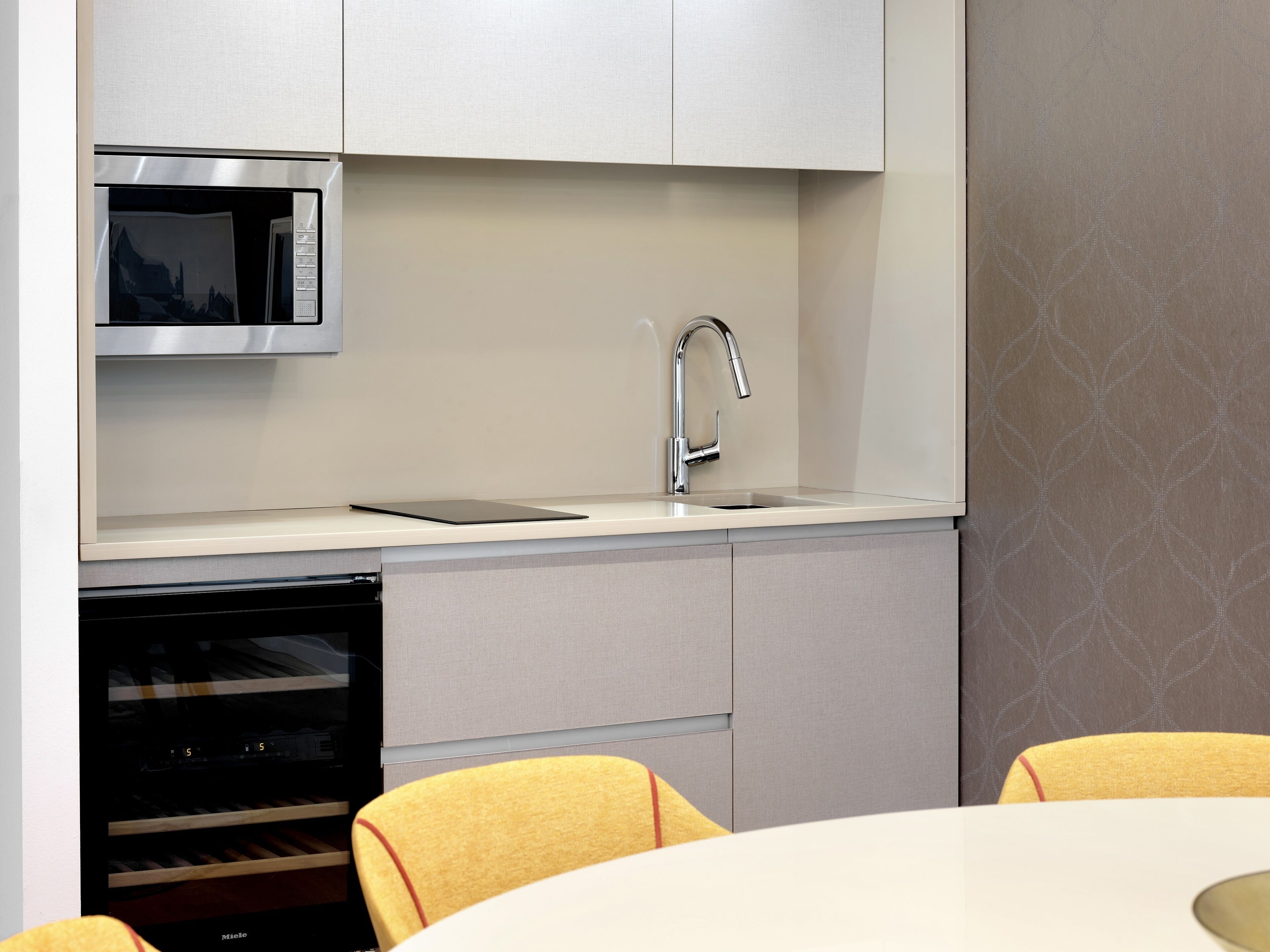 A modern kitchen with a built-in microwave, stainless steel faucet, and a wine cooler.