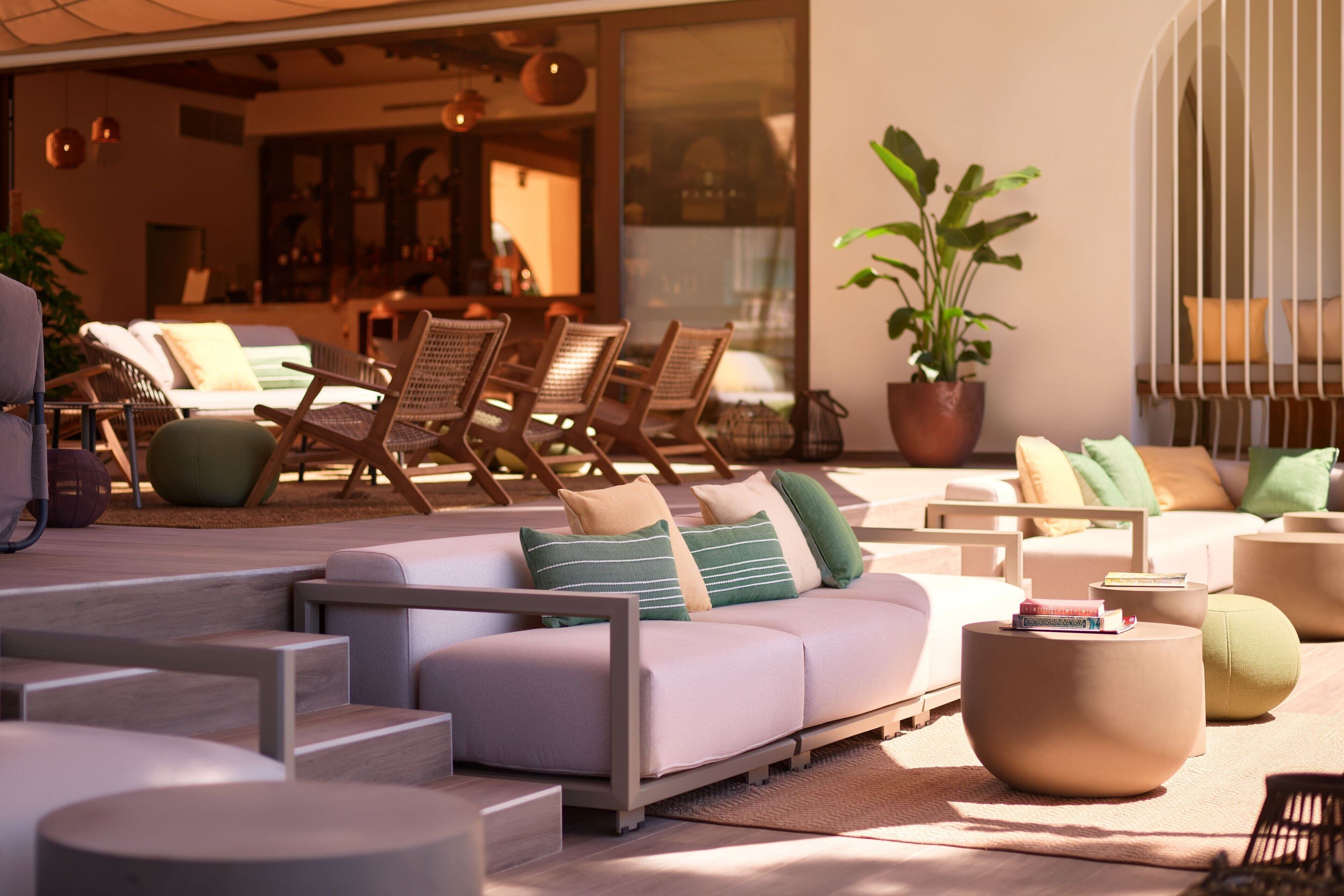 Een moderne buitenlounge met een bank, stoelen en ronde tafels.