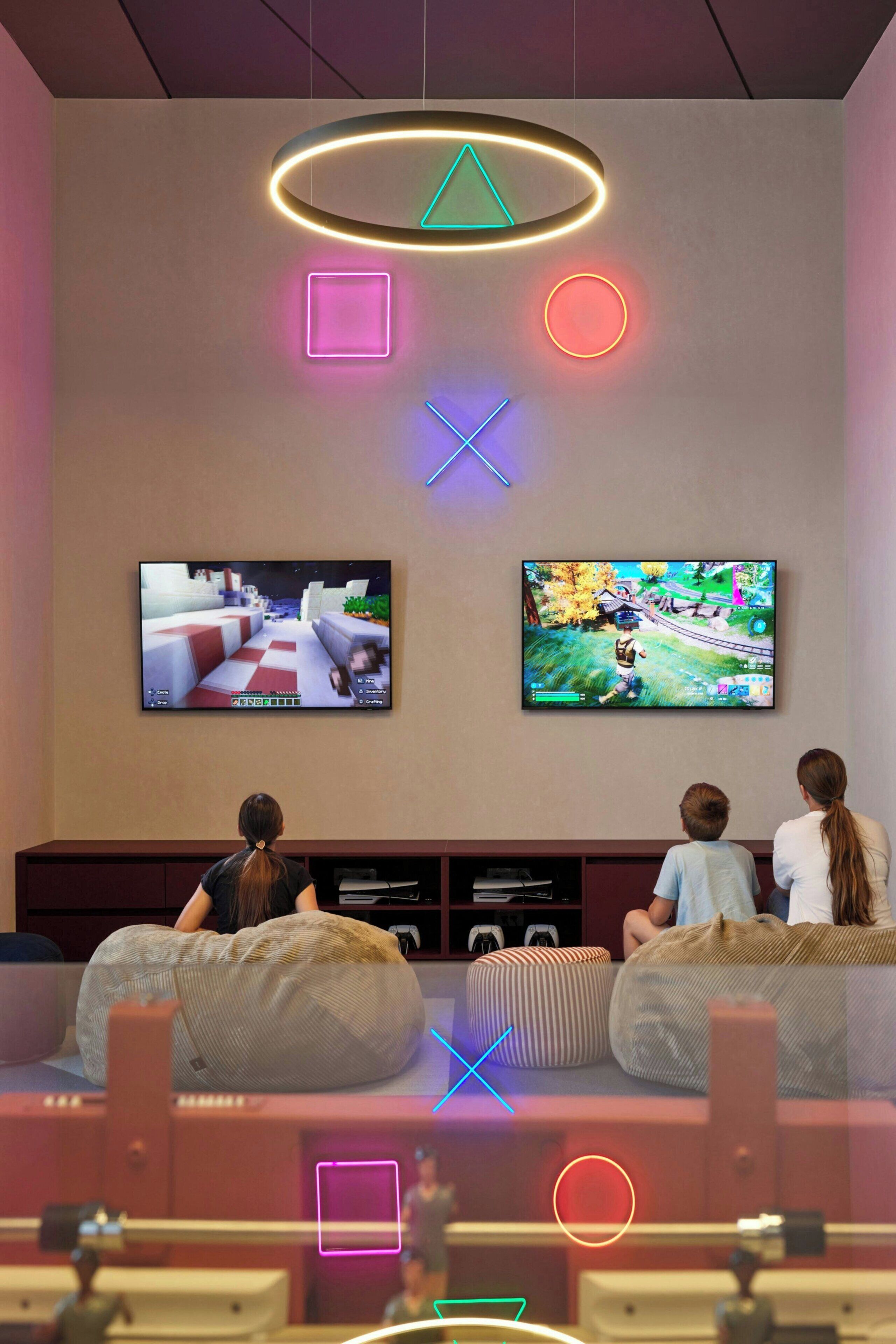 A living room with two bean bag chairs, a flat-screen TV, and a neon light fixture.
