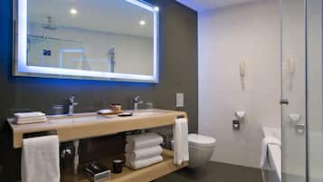 Un baño moderno con un espejo grande, dos lavamanos, un inodoro y una cabina de ducha de vidrio.