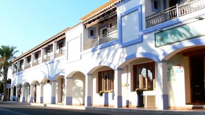 A two-story building with a white facade, multiple balconies, and a tiled roof. - Hostal LA Savina (Formentera)