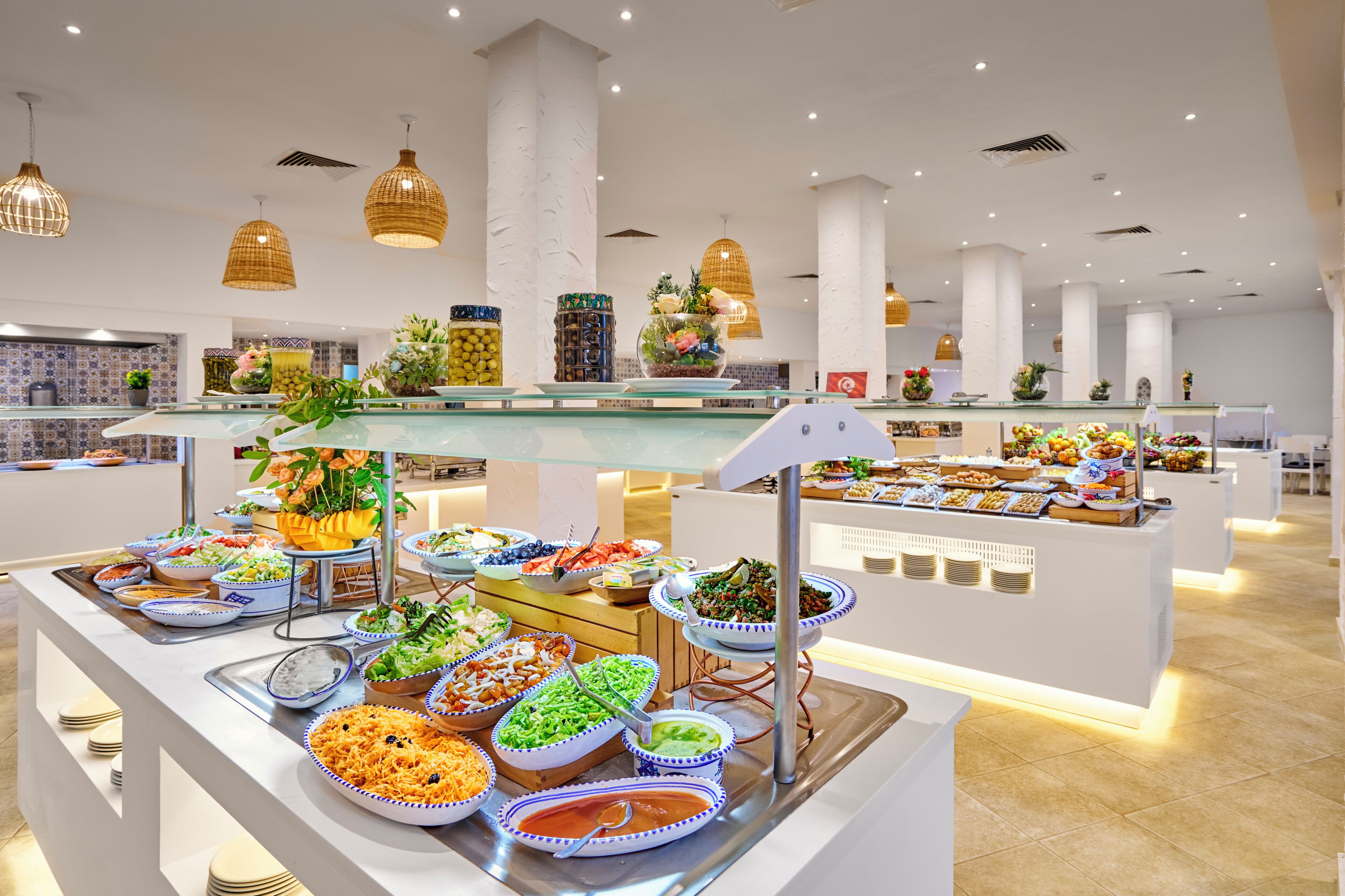 A buffet with various food items, a glass display case, and hanging pendant lights.