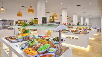 A buffet with various food items, a glass display case, and hanging pendant lights.
