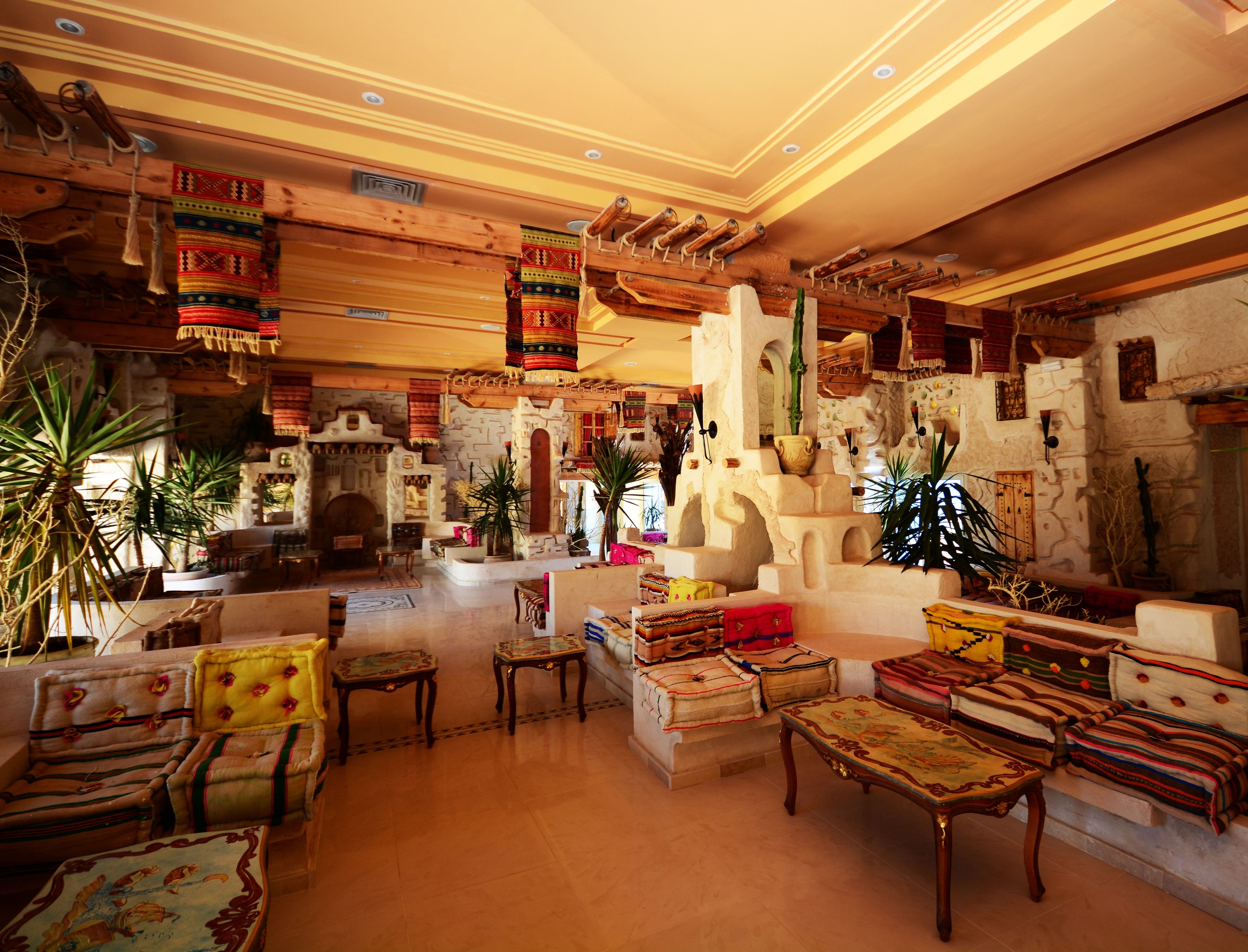 Un hall d’entrée spacieux, décoré dans un style traditionnel, avec notamment une cheminée en pierre, des meubles en bois et des textiles suspendus.