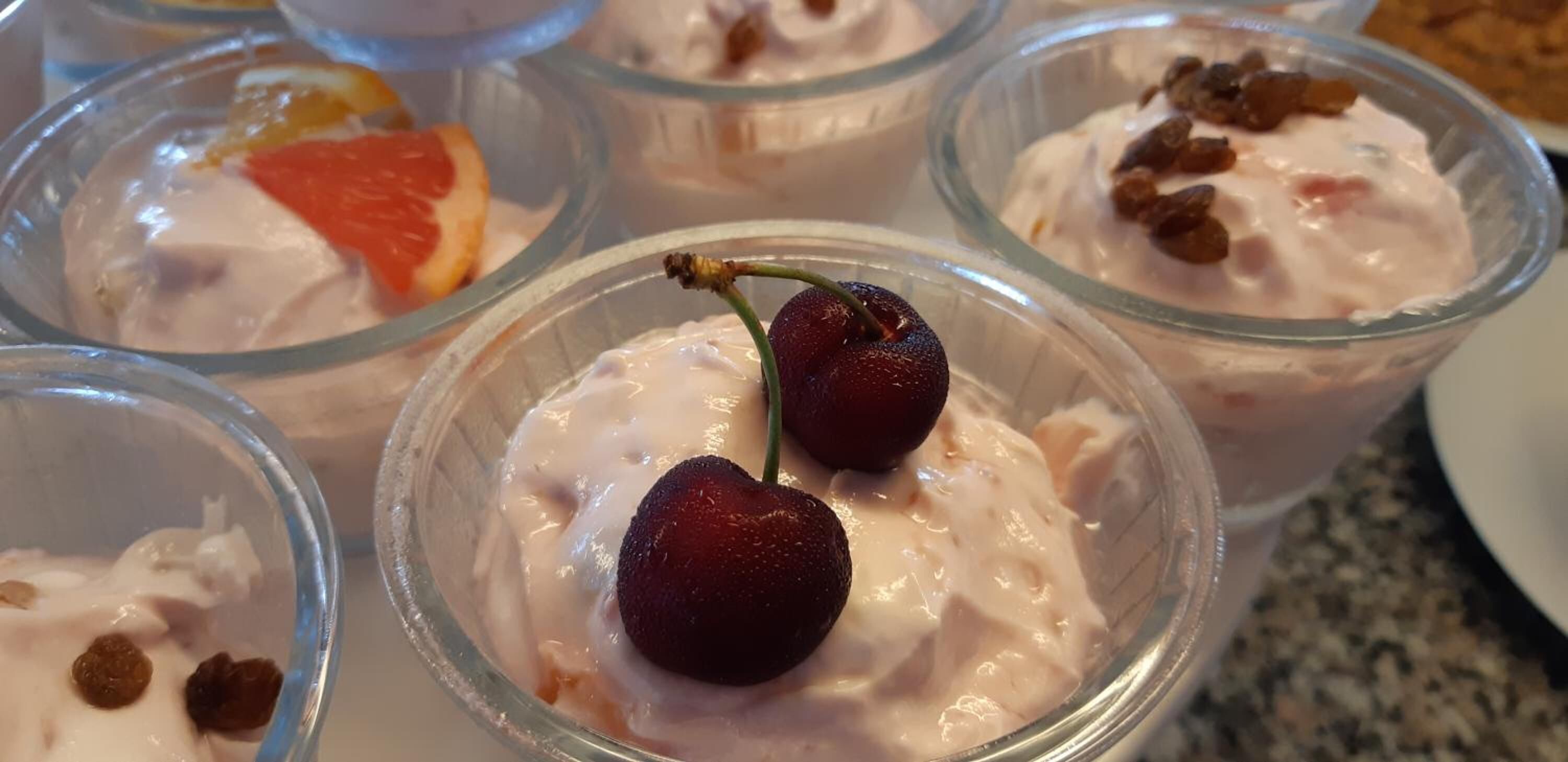 A dessert tray with various fruit-topped desserts in clear glass cups.