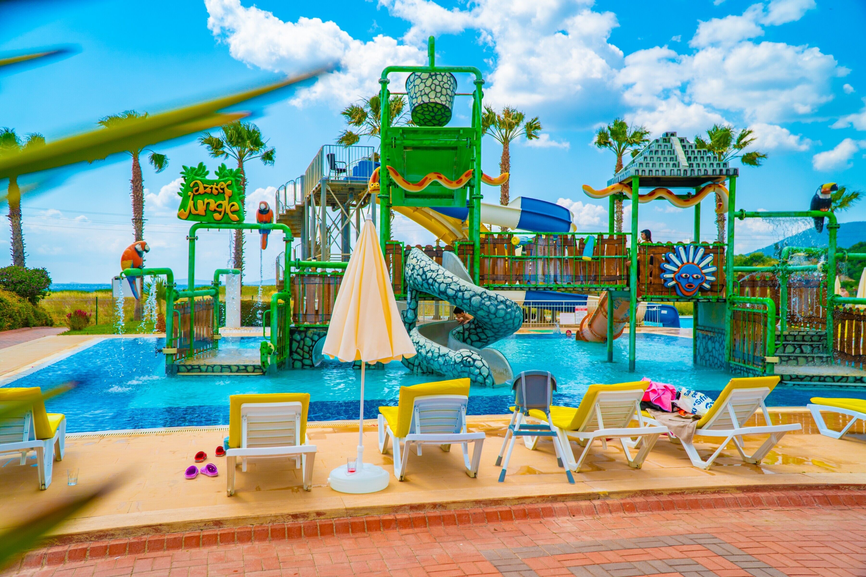 A water park with slides, a pool, and lounge chairs.