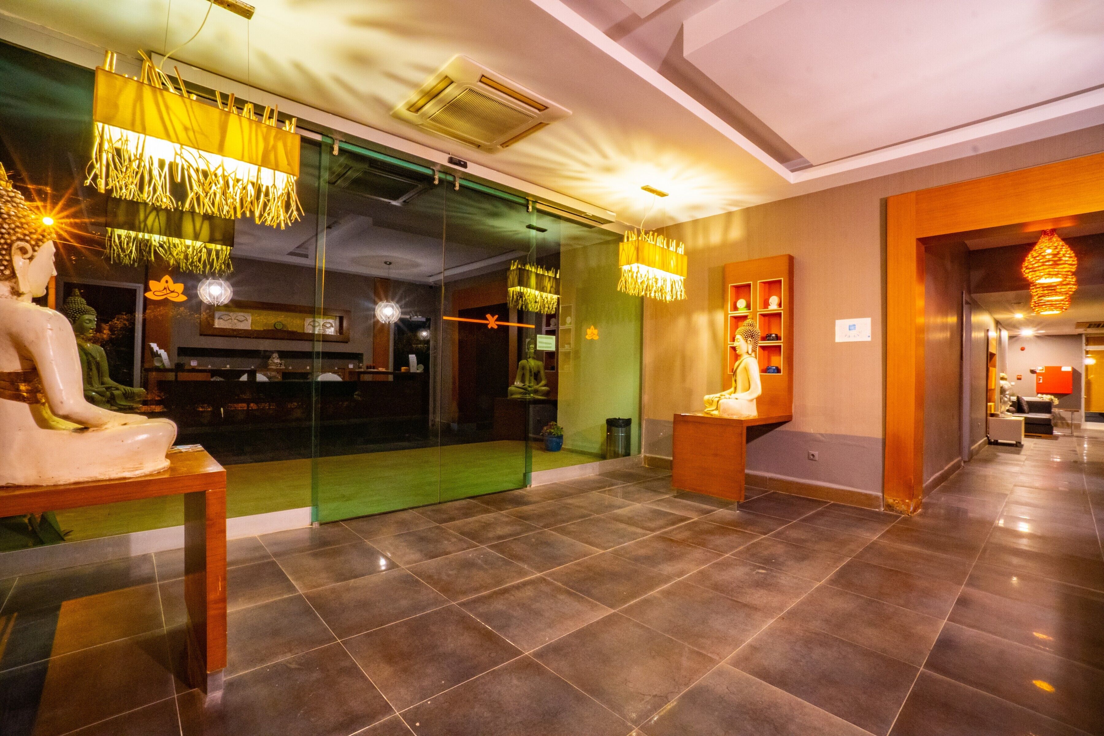 A lobby with a Buddha statue, a reception desk, and a modern chandelier.
