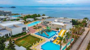 Relax by the resort's large pool, featuring a water slide and kids' play area, surrounded by lush greenery and sea views.
