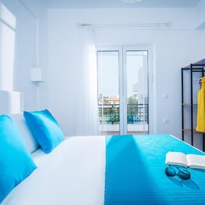 A hotel room with a bed, a balcony, and a view of the city. - W Suites (Hersonissos)
