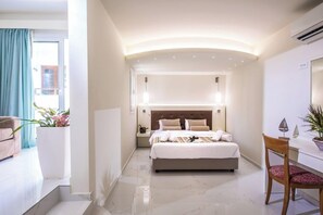 A hotel room with a bed, bedside table, chair, and a view of the outside. - W Suites (Hersonissos)