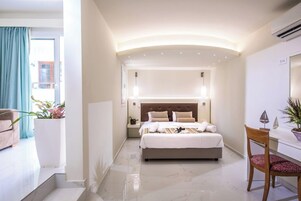 Una habitación de hotel con cama, mesita de noche, silla y vistas al exterior.