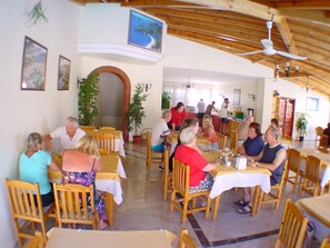 A restaurant with wooden tables and chairs, a brick archway, and a ceiling fan. - Belcehan Beach (Fethiye)