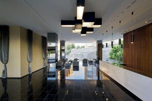 A modern lobby with a reflective floor, seating area, and a view of a waterfall.