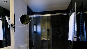 A modern bathroom with a glass shower enclosure, a white sink, and a toilet.