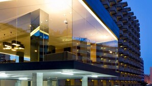 A modern hotel with a glass facade, multiple balconies, and a structured, geometric design.