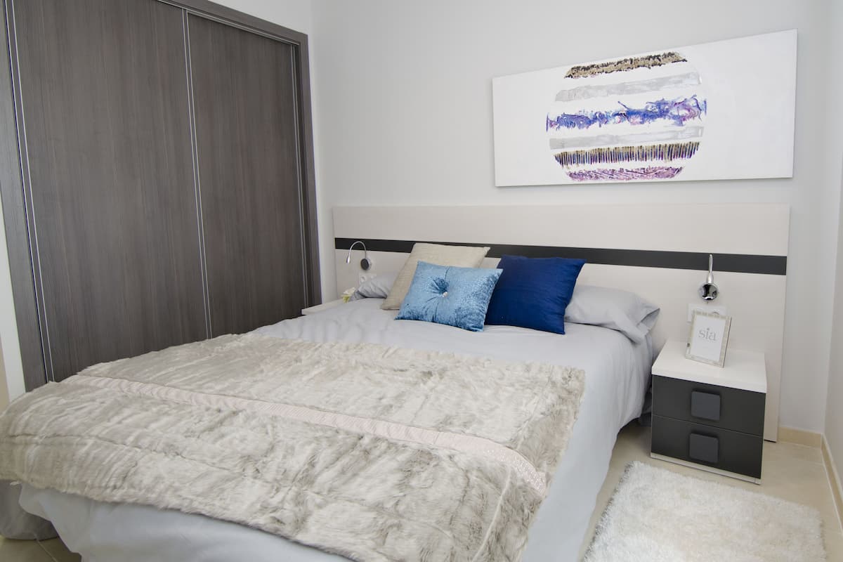 Une chambre à coucher comprenant un lit, une table de chevet, une commode, un tableau encadré et une armoire.