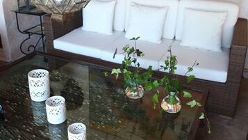 Una sala de estar moderna con una mesa de centro de vidrio, sofá blanco, un farol decorativo y un cuadro grande con motivos florales en la pared.
