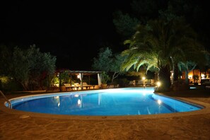 Een seizoensgebonden buitenzwembad en ligstoelen