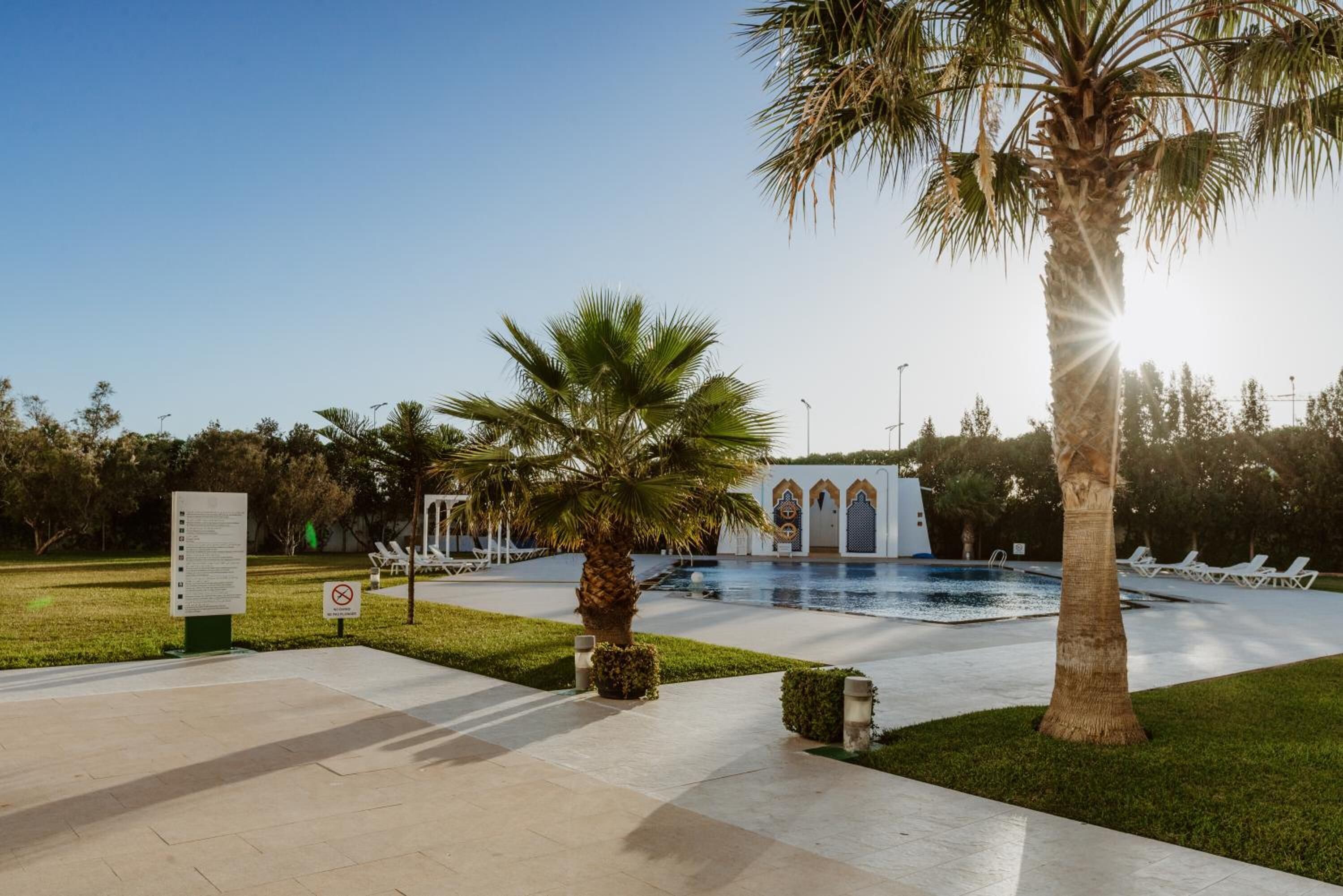 Una piscina al aire libre, sombrillas, sillones reclinables de piscina