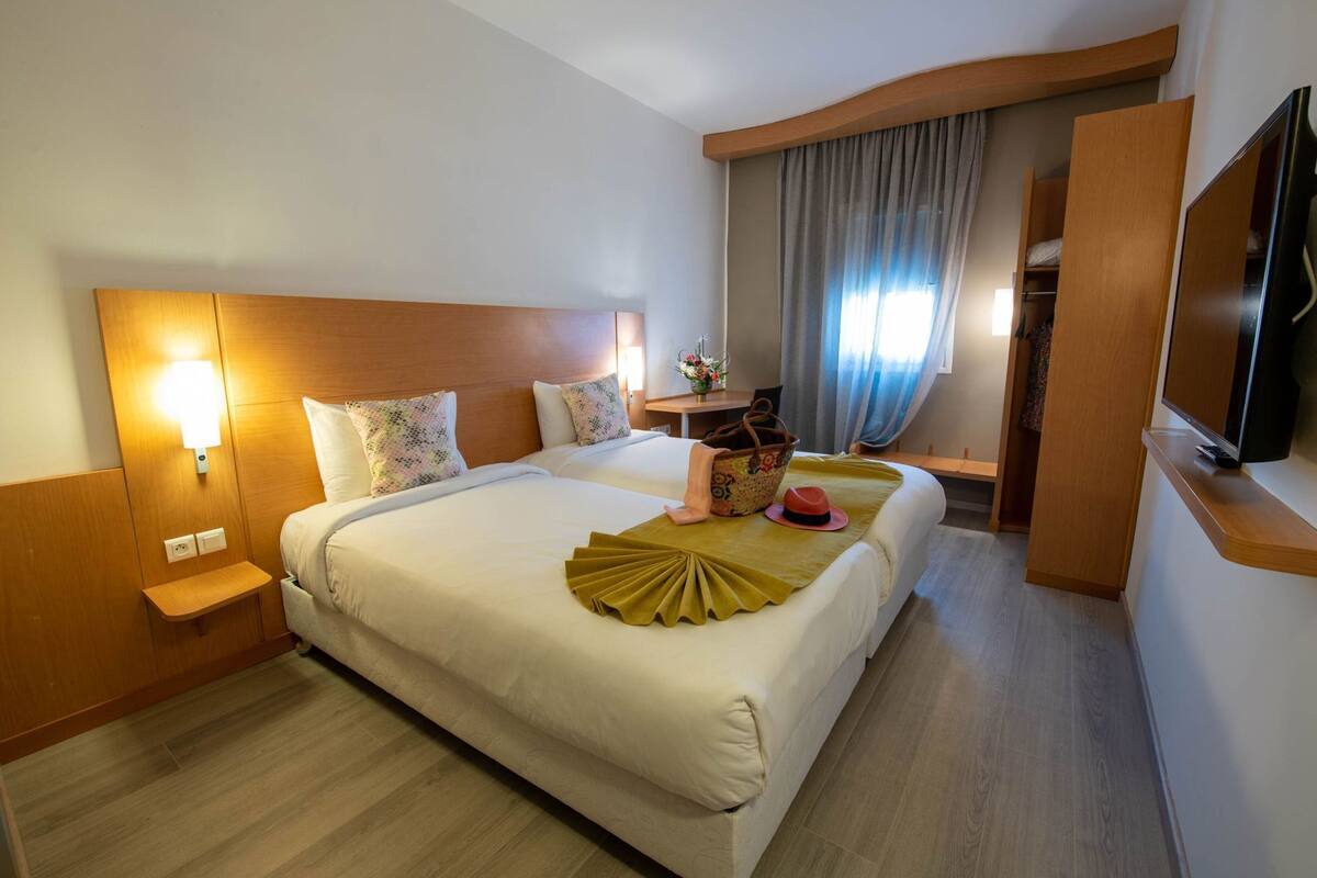 Une chambre d’hôtel avec un grand lit, des tables de chevet, une télévision et un bureau avec une chaise.
