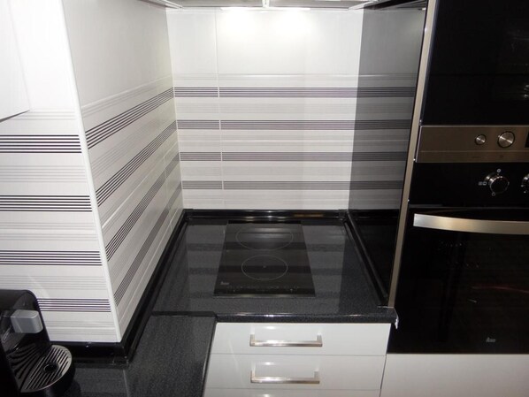 A kitchen with a black stovetop, white cabinets, and a stainless steel oven. - Clube DOS Arcos (Portimao)