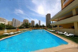 A swimming pool with lounge chairs and a view of tall buildings in the background. - Clube DOS Arcos (Portimao)