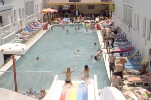 Una piscina al aire libre, sombrillas, sillones reclinables de piscina
