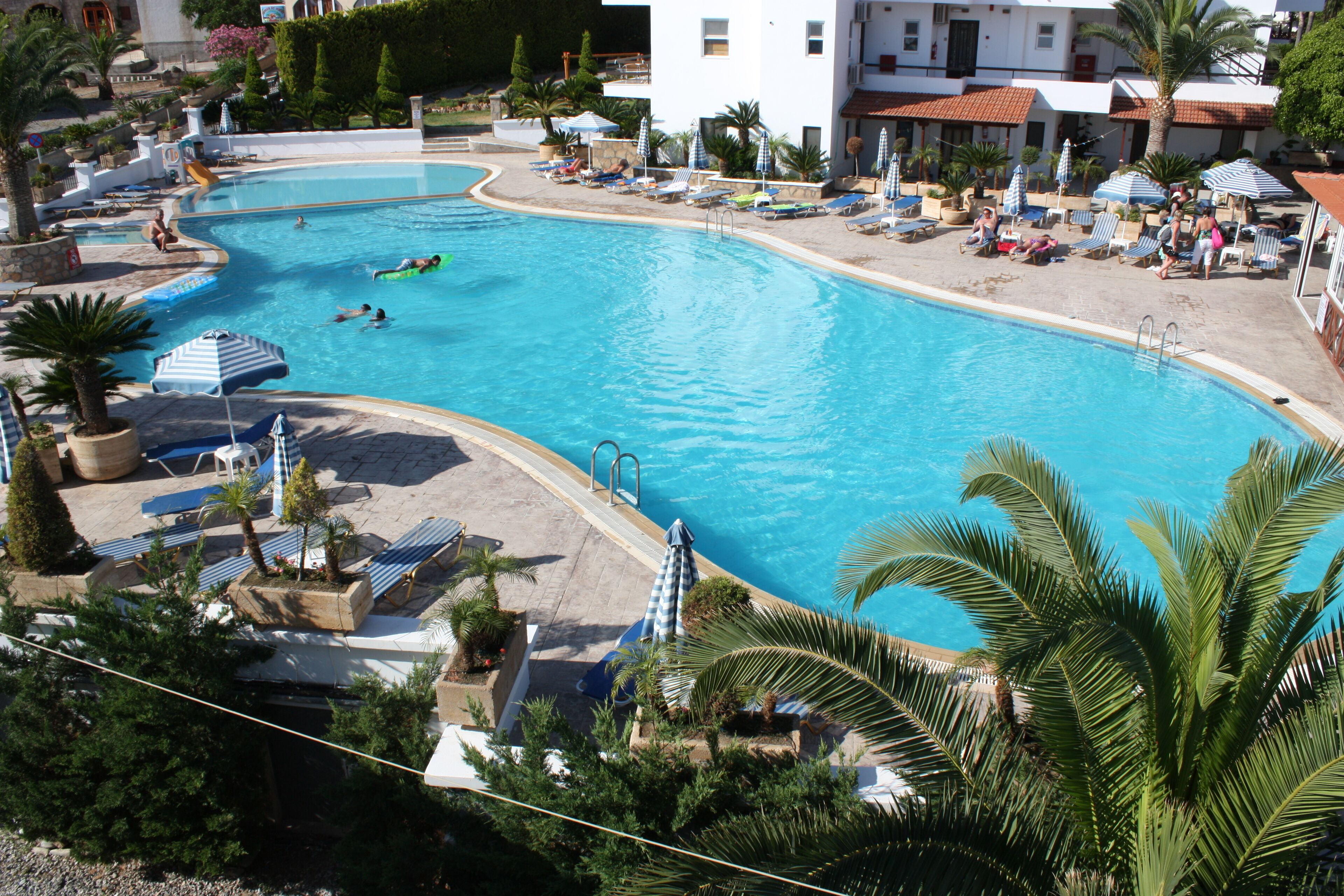 Una gran piscina amb diverses línies, envoltada de gandules i para-sols.