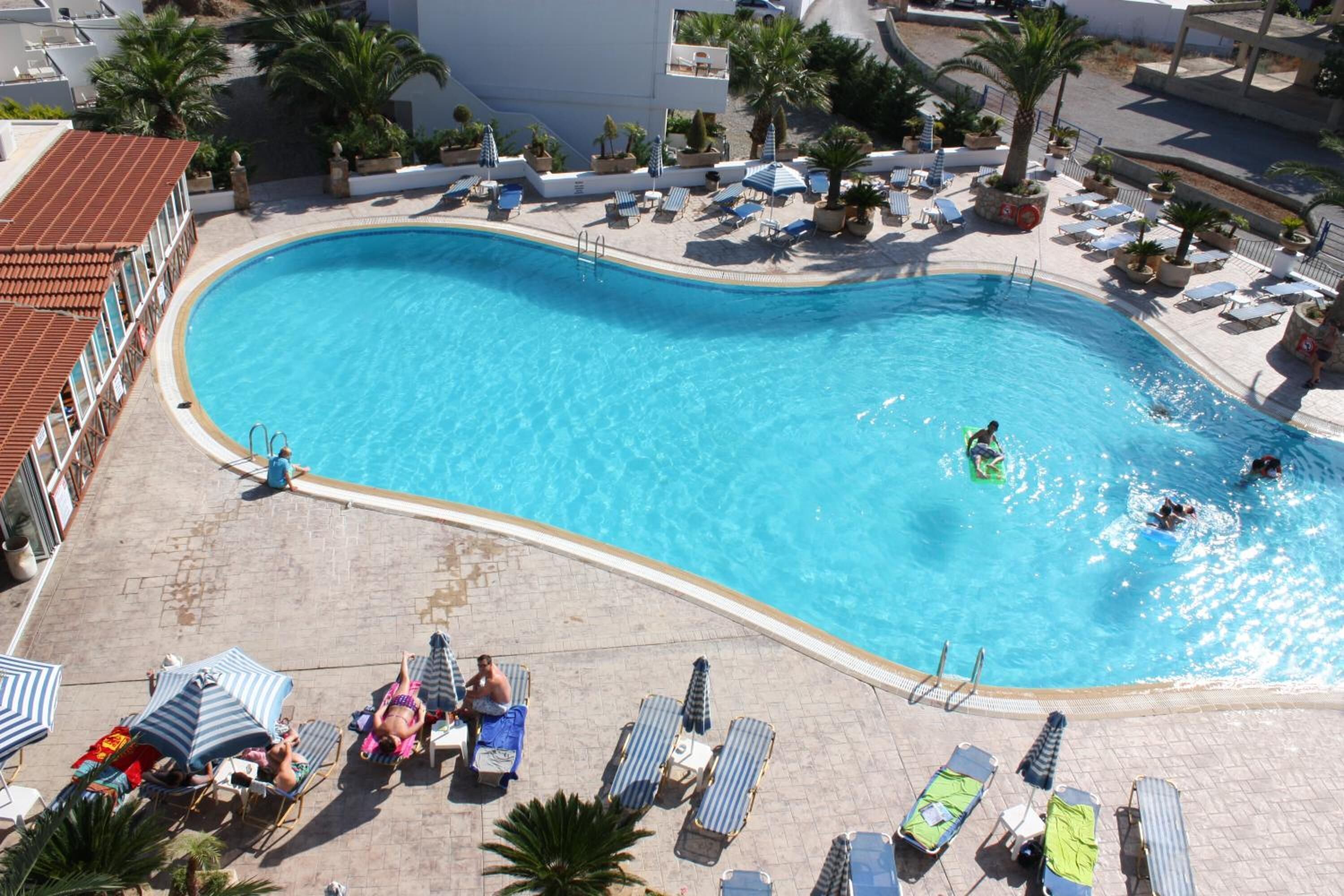 A large, curved swimming pool with lounge chairs and umbrellas around it.
