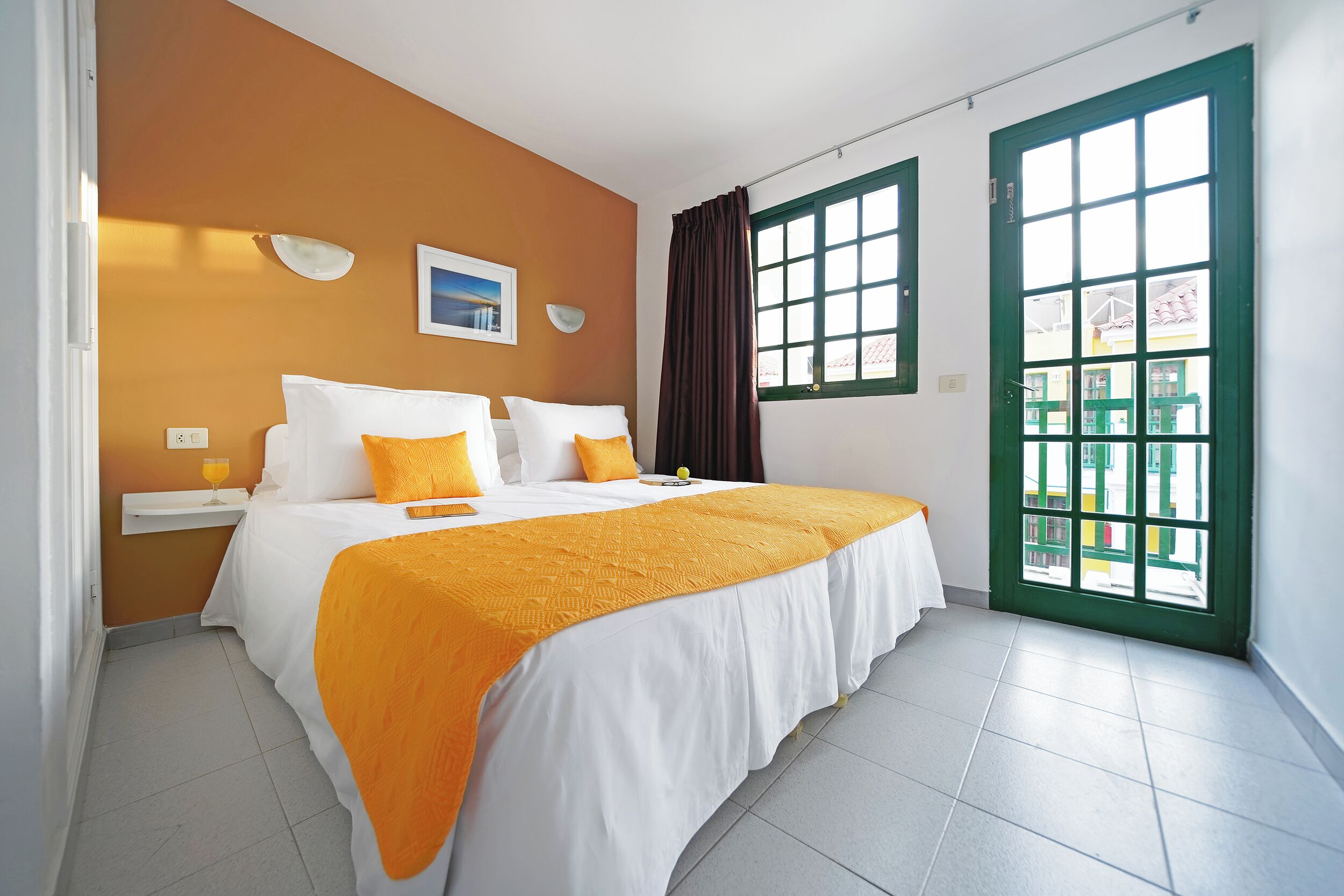 Habitación de hotel con cama, mesita de noche, ventana con cortinas y vista al exterior.