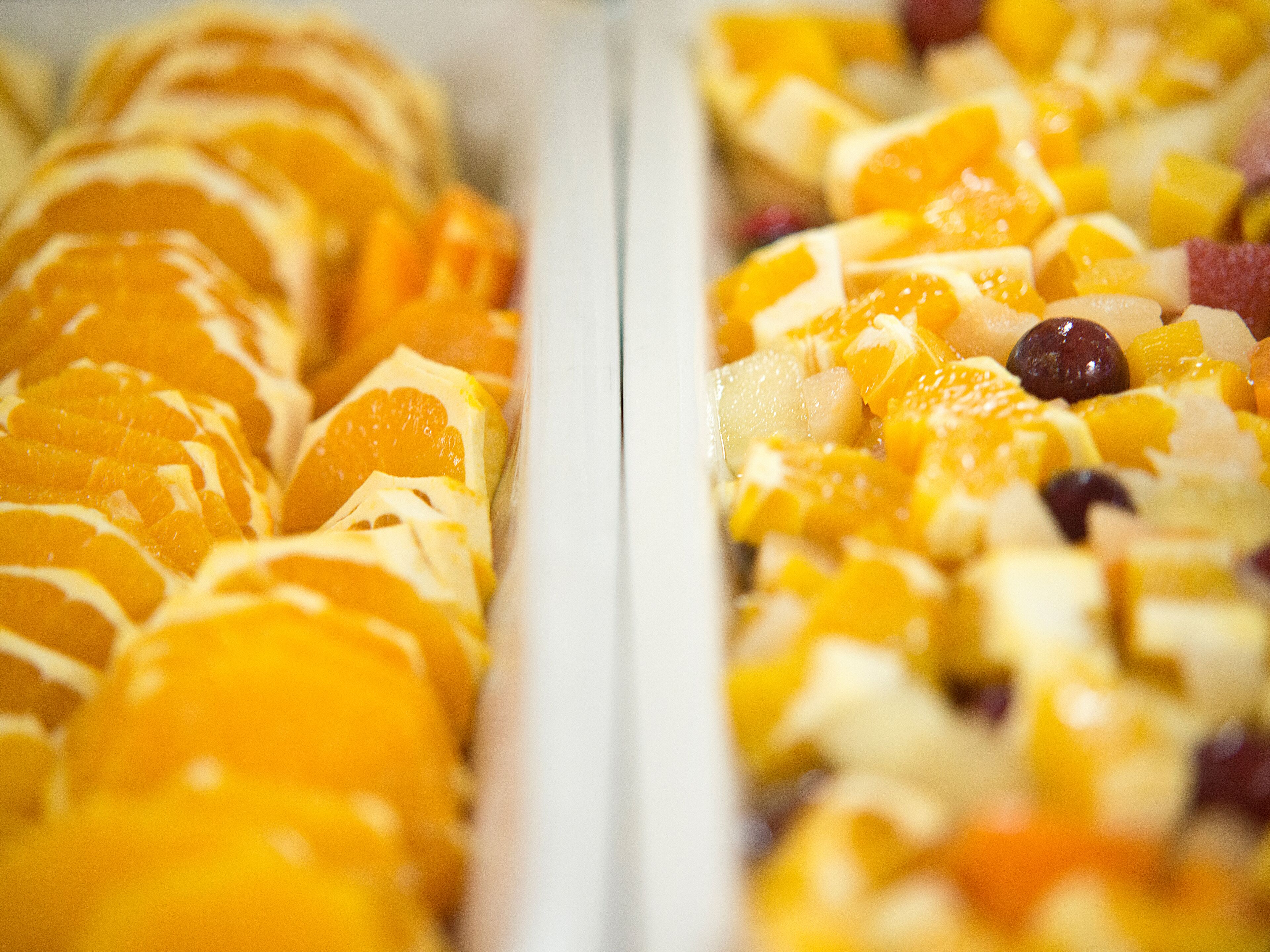 Una bandeja de frutas con mandarinas en rodajas y otras frutas.