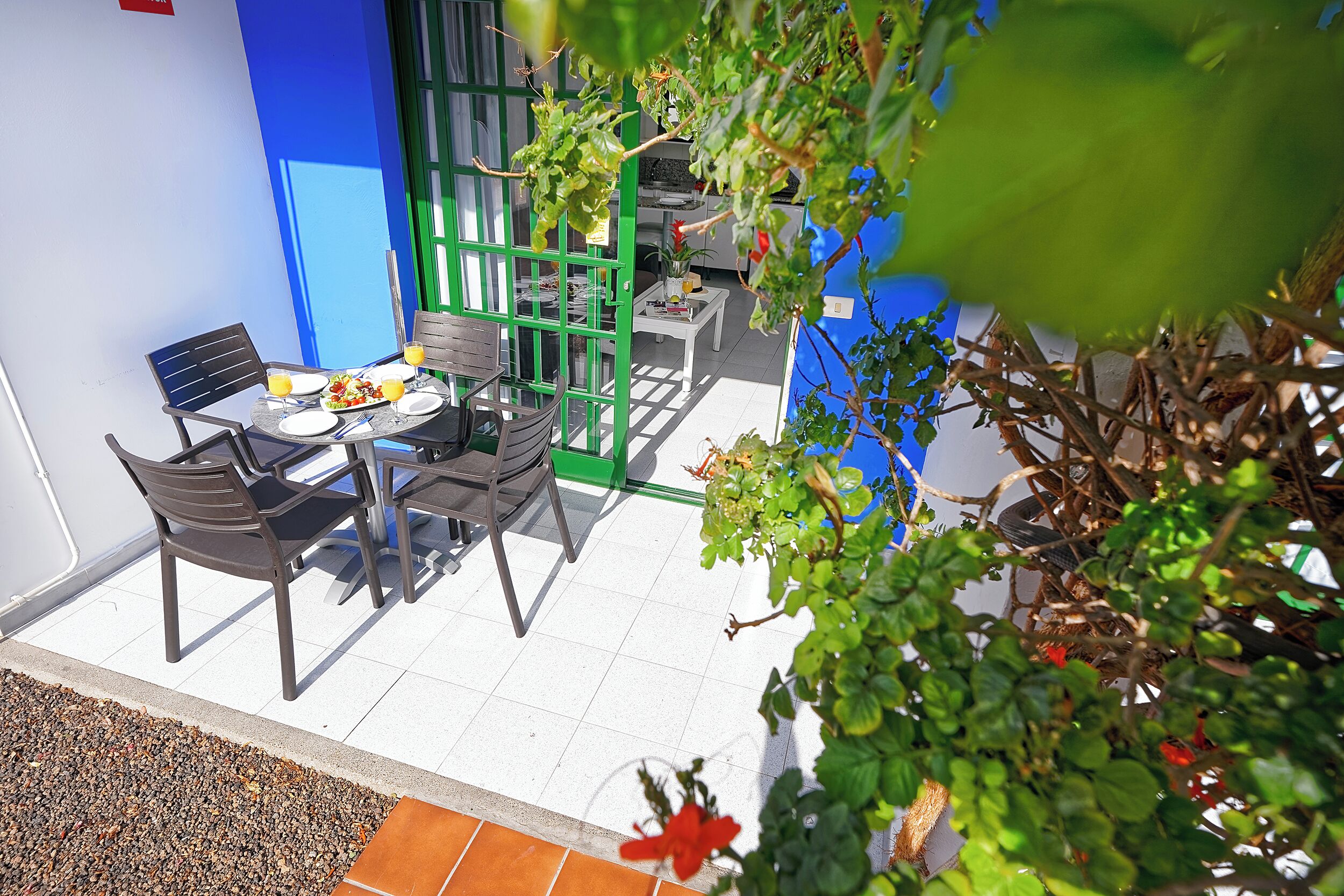 An outdoor dining area with a table, chairs, and a green partition.