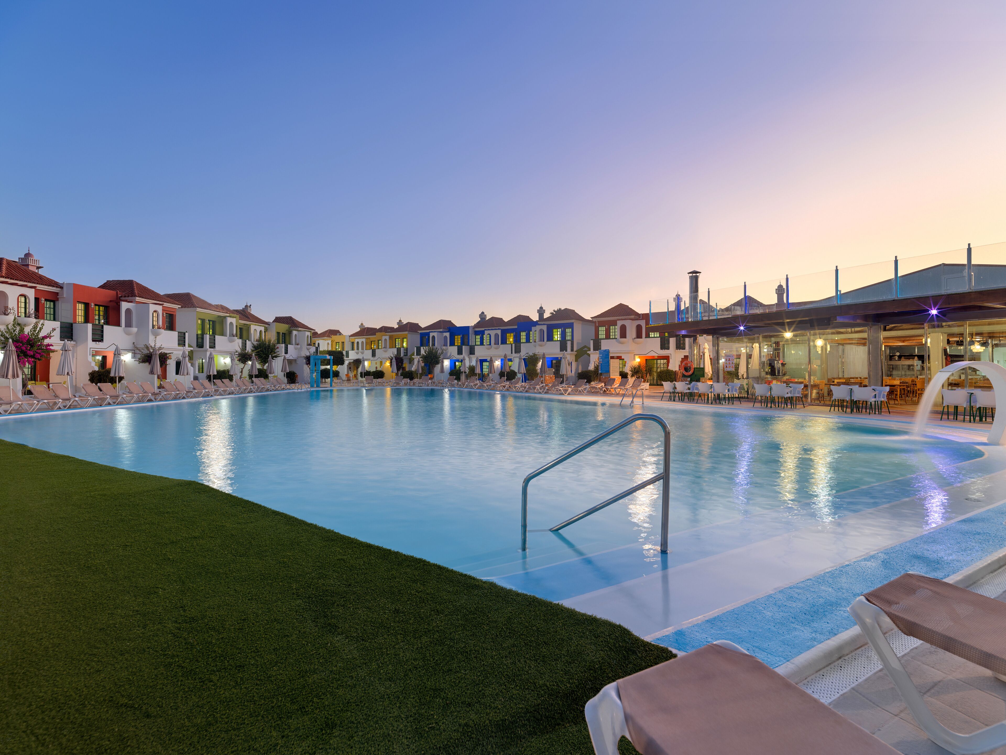 A swimming pool with lounge chairs and a restaurant area.